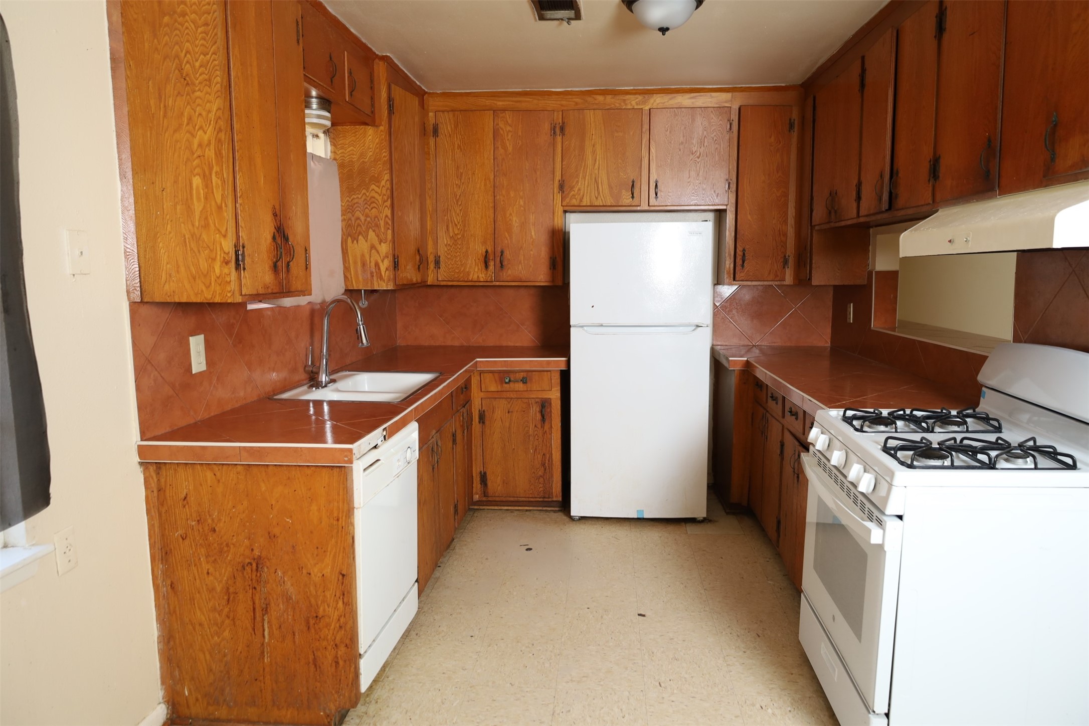 13207 Santa Teresa Road Houston, TX 77045 - Photo 7 of 20 a kitchen with a refrigerator a stove top oven a sink and cabinets