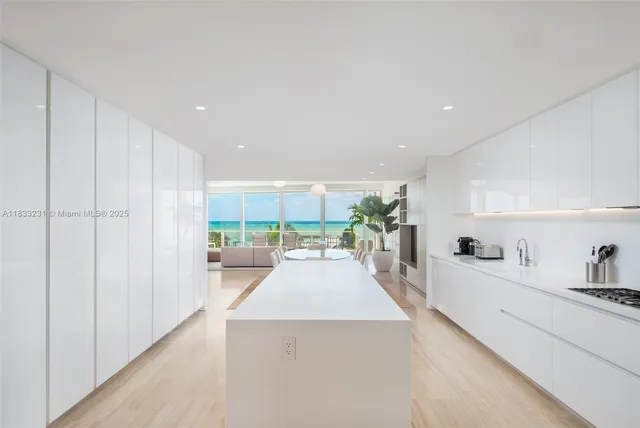 a large white kitchen with kitchen island a large counter space a sink a stove and white cabinets