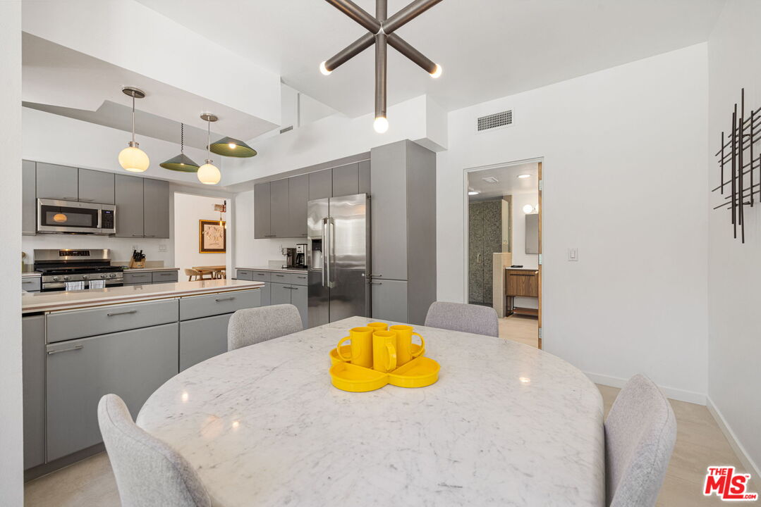 1414 Sagebrush Road Palm Springs, CA 92264 - Photo 24 of 48 a kitchen with stainless steel appliances a kitchen island a stove a refrigerator cabinets and a dining table
