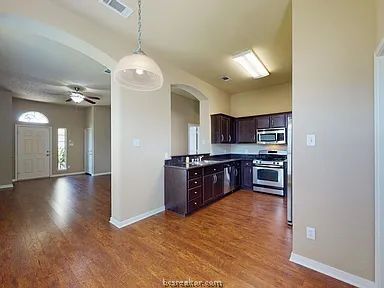 2024 Mountain Wind Loop Bryan, TX 77807 - Photo 4 of 14 a kitchen with stainless steel appliances granite countertop a refrigerator and a wooden floors