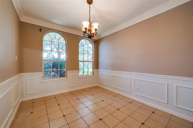 a view of an empty room with window and chandelier