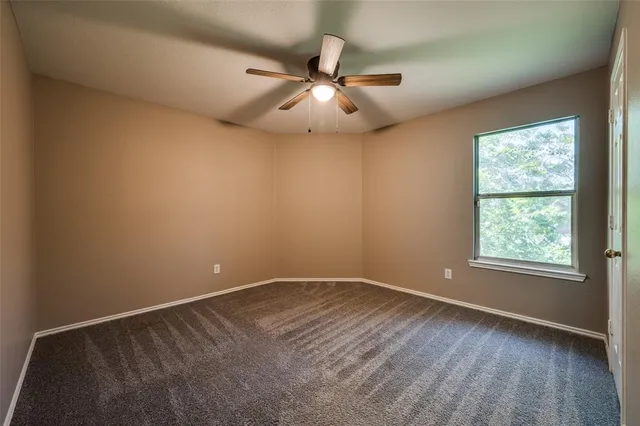 an empty room with a window and a ceiling fan