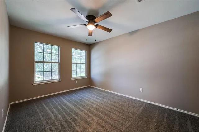 an empty room with windows and ceiling fan