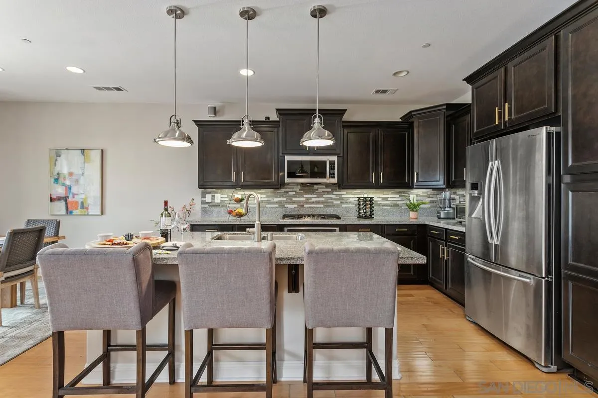 1014 Bellingham Drive Oceanside, CA 92057 - Photo 4 of 33 a kitchen with kitchen island a dining table chairs and a refrigerator