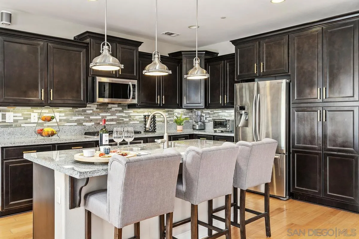 1014 Bellingham Drive Oceanside, CA 92057 - Photo 9 of 33 a kitchen with stainless steel appliances granite countertop a stove top oven a refrigerator a sink and a dining table with chairs