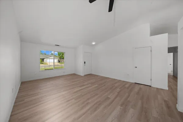a view of an empty room with wooden floor and windows