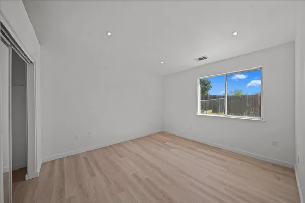 a view of empty room with window and wooden floor
