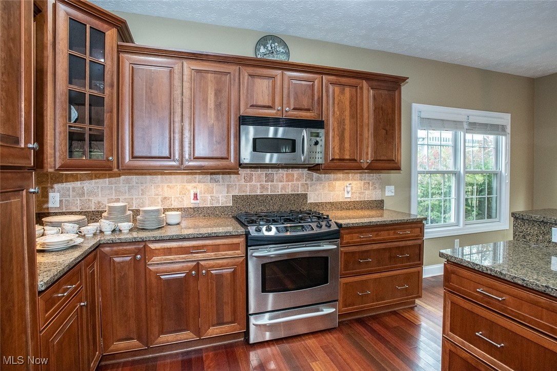 630 Rundle Street Lagrange, OH 44050 - Photo 13 of 49 Kitchen featuring stainless steel appliances, light stone countertops, backsplash, a textured ceiling, and dark wood-style flooring