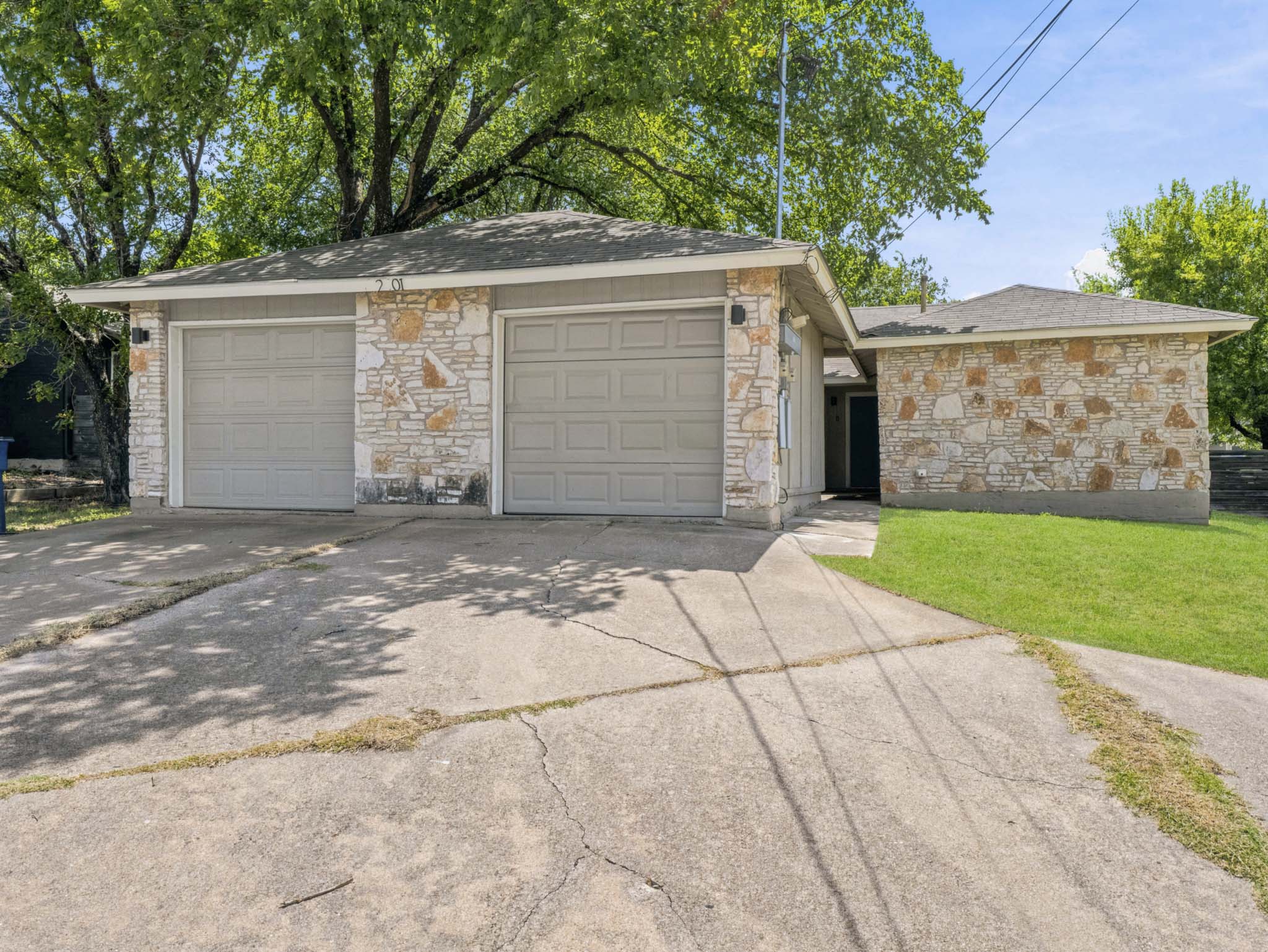 2401 Burleson Road Austin, TX 78741 - Photo 1 of 25 A stone-accented facade introduces this charming home, featuring a practical attached garage and concrete driveway.