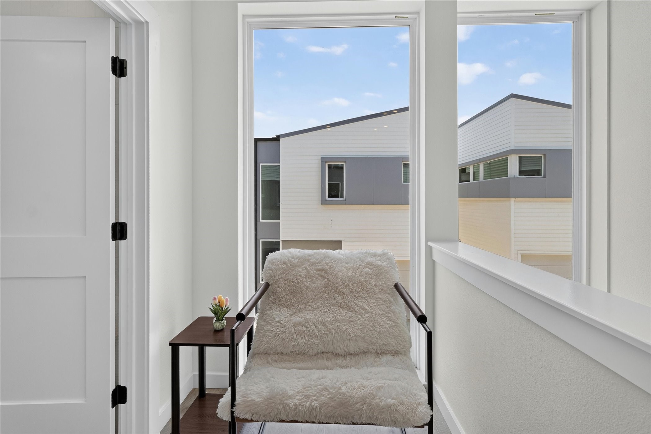 2000 Riverside Farms Road, Unit 8101 Austin, TX 78741 - Photo 13 of 41 This photo shows a cozy nook with a soft chair and side table, framed by large windows offering a view of modern neighboring buildings.