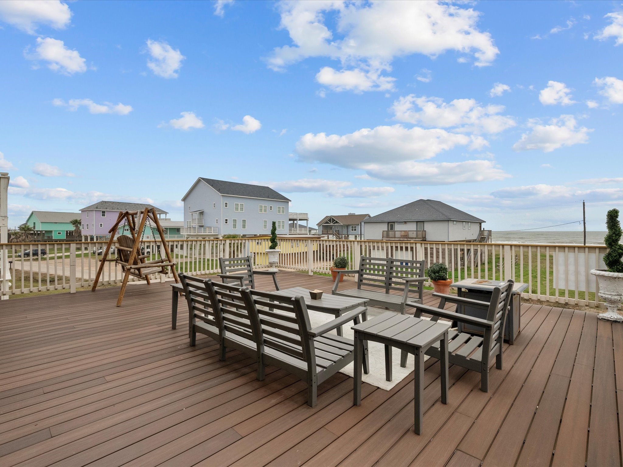 1018 Seashell Drive Surfside Beach, TX 77541 - Photo 48 of 49 Expansive wooden deck with modern outdoor seating, perfect for entertaining. Offers partial ocean views and a serene neighborhood setting, ideal for relaxation.