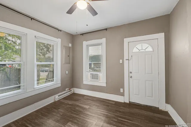 a view of an empty room with wooden floor and a window