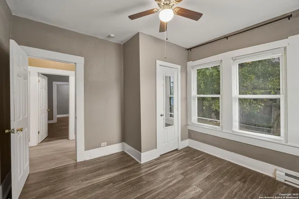 a view of an empty room with a window and wooden floor