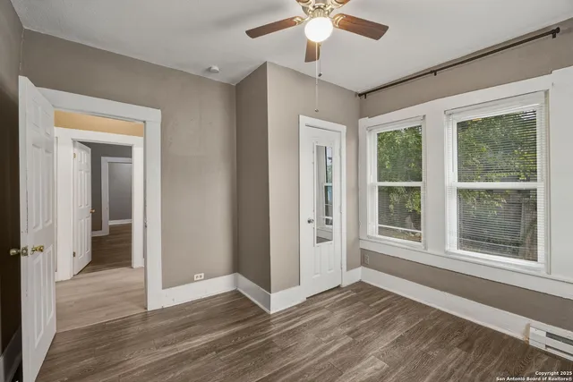 a view of an empty room with a window and wooden floor