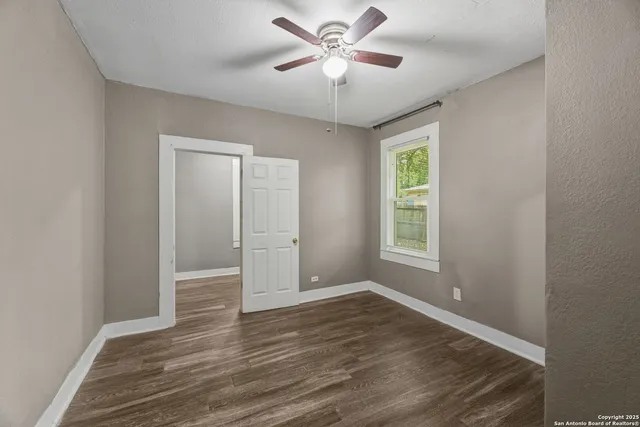 a view of an empty room with a window and wooden floor