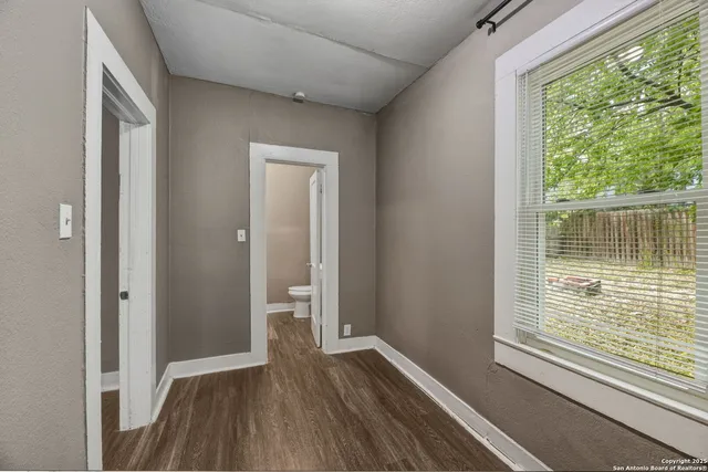 a view of an empty room with wooden floor and a window