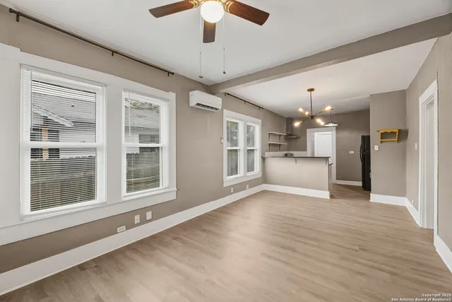 a view of an empty room with kitchen and a window