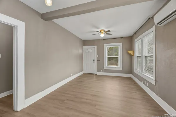 a view of an empty room with a window and wooden floor