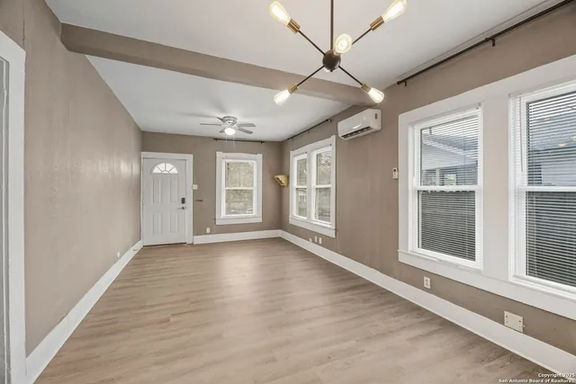 a view of an empty room with a window and wooden floor