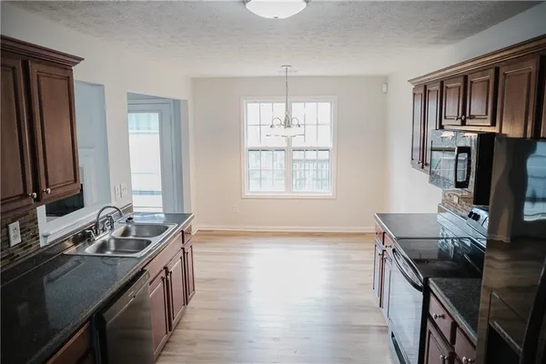 a kitchen with stainless steel appliances granite countertop a sink stove and cabinets