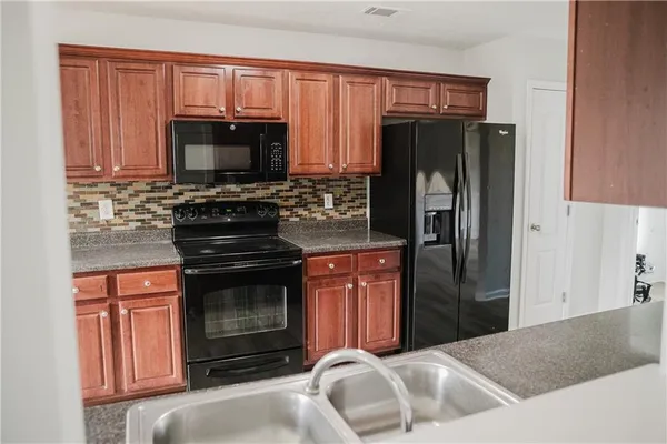 a kitchen with granite countertop a stove microwave and refrigerator