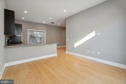 a view of kitchen with stainless steel appliances granite countertop a sink and a wooden floor