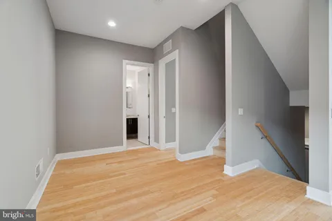a view of empty room with wooden floor and fan