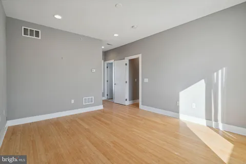 an empty room with wooden floor and windows