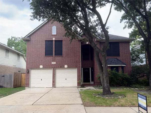 a front view of a house with a yard and tree