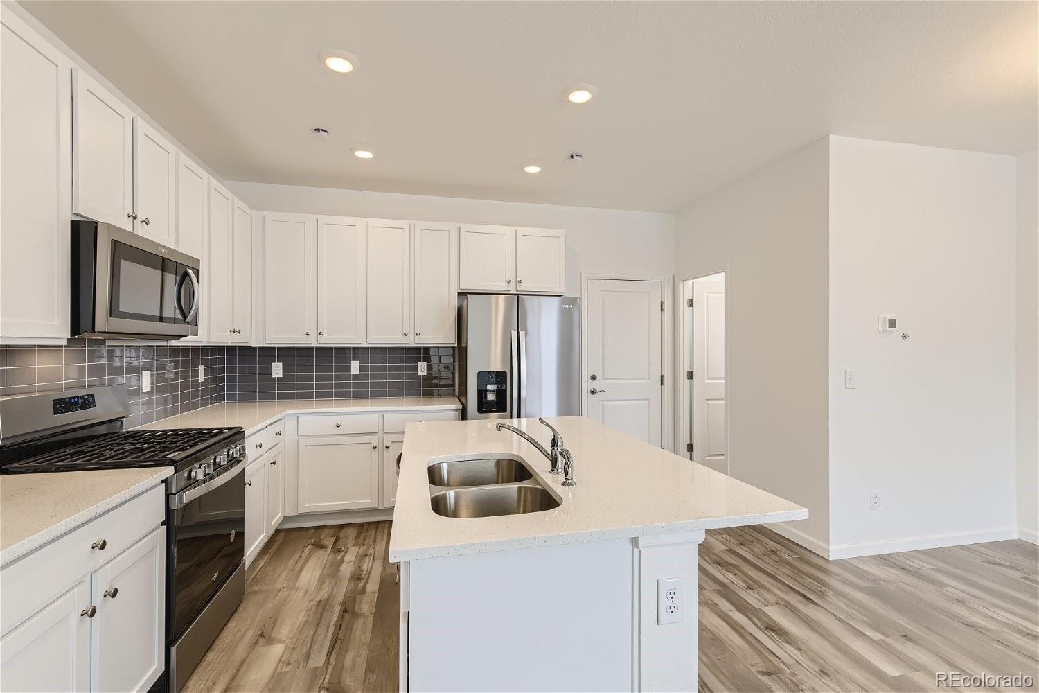 12659 Boggs Street Parker, CO 80134 - Photo 12 of 28 a kitchen with kitchen island a sink stainless steel appliances and cabinets