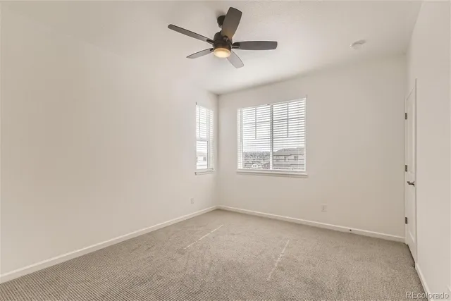 an empty room with a window and a ceiling fan
