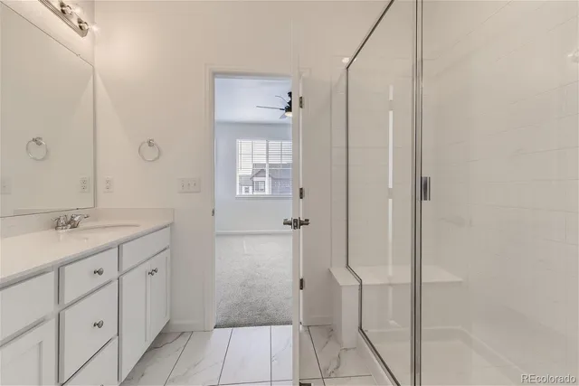 a bathroom with a granite countertop sink two mirror and a shower