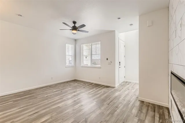 an empty room with wooden floor ceiling fan and windows
