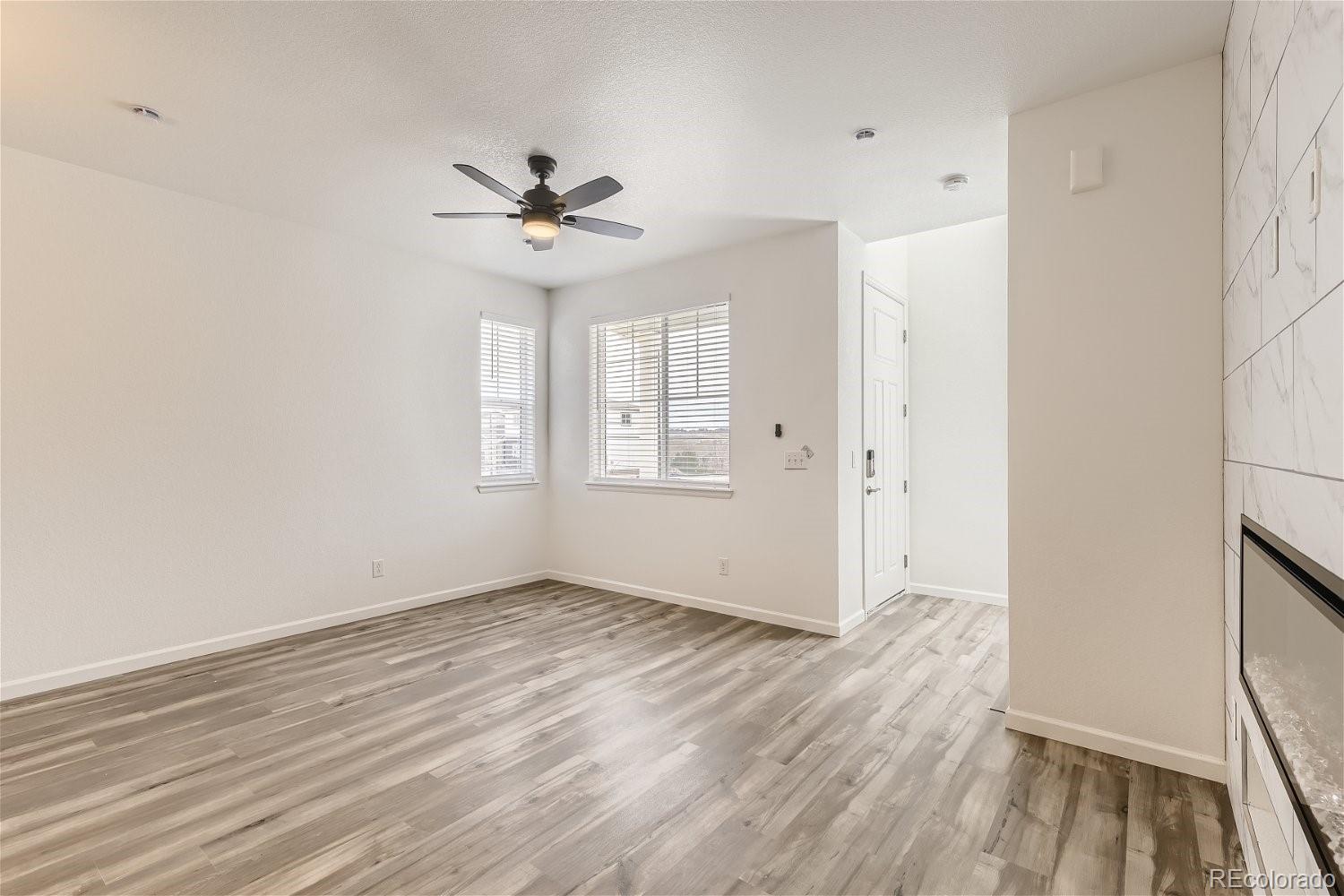 12659 Boggs Street Parker, CO 80134 - Photo 7 of 28 an empty room with wooden floor ceiling fan and windows