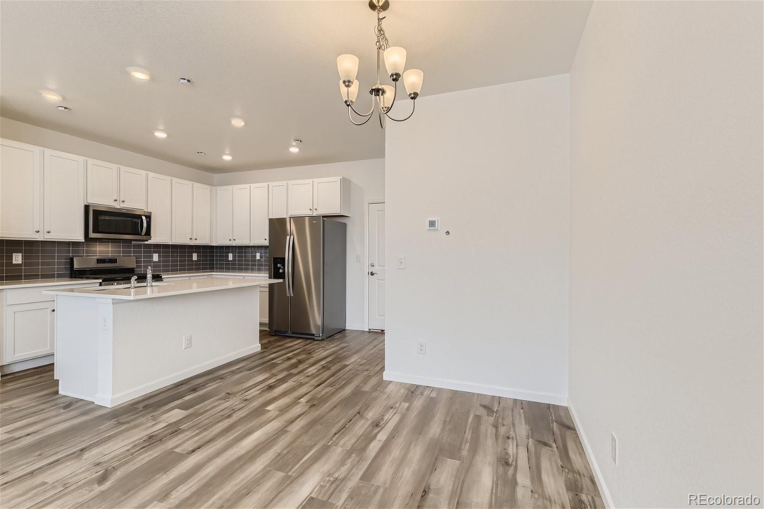 12659 Boggs Street Parker, CO 80134 - Photo 9 of 28 a kitchen with a refrigerator and a stove top oven