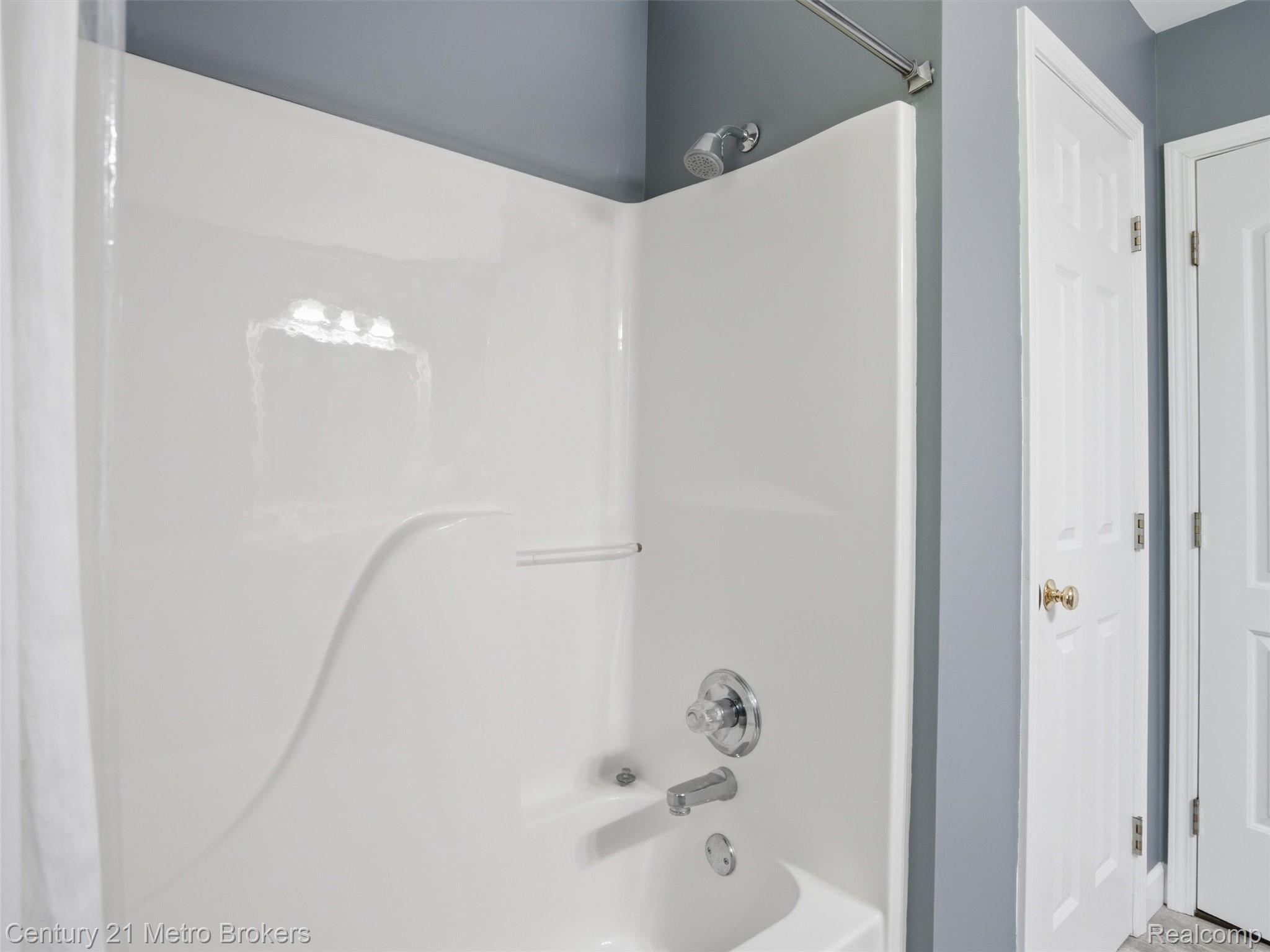 11447 North Latson Road Linden, MI 48451 - Photo 17 of 52 White bathtub and shower combination unit featuring chrome fixtures and a built-in soap dish