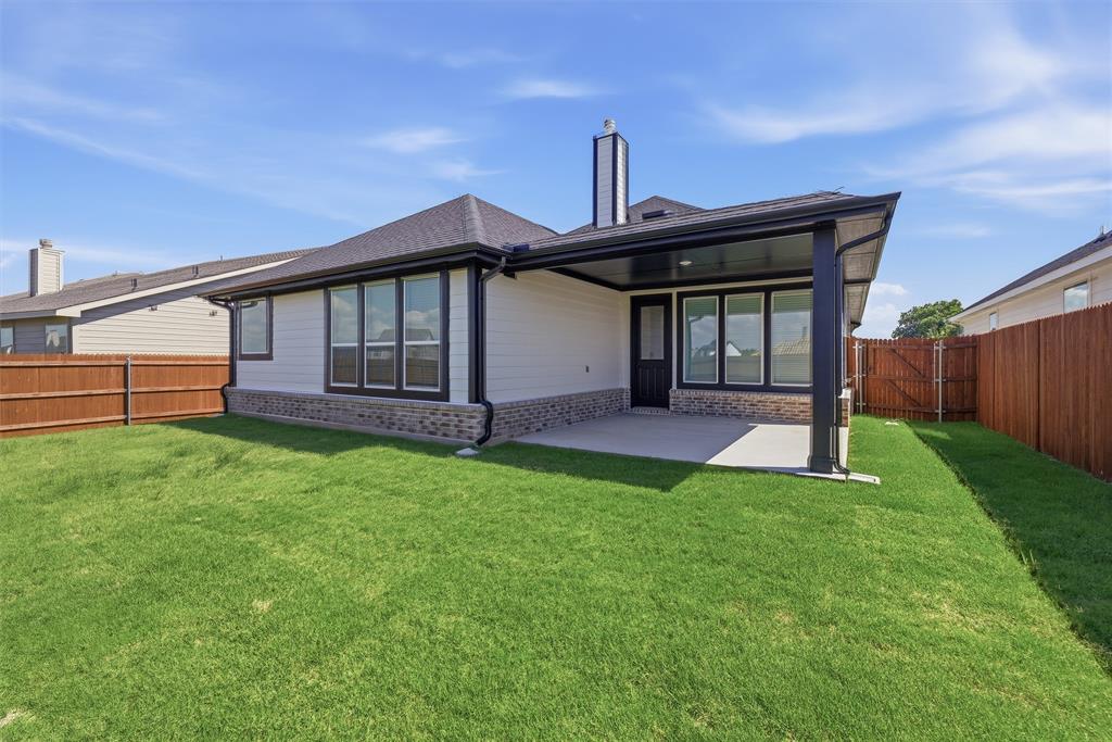 1213 Colca Drive Springtown, TX 76082 - Photo 20 of 23 Expansive backyard featuring a covered patio with concrete flooring, white siding, stone veneer accents, and a dark shingle roof