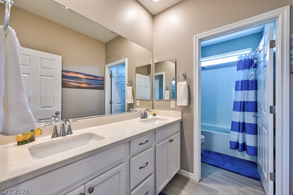 1054 Langston Ranch Avenue Henderson, NV 89002 - Photo 42 of 82 Bathroom for bedrooms 2 and 3 featuring a double vanity, medicine cabinets and painted cabinetry with knobs and pulls. The shower/ bath combination and toilet are in a separate room with a door for privacy.