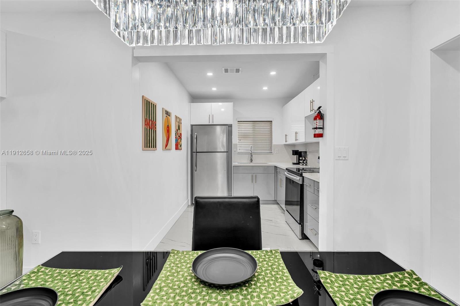 797 Northwest 35th Street Miami, FL 33127 - Photo 11 of 45 a kitchen with stainless steel appliances granite countertop a refrigerator a stove a sink and a dining table with wooden floor