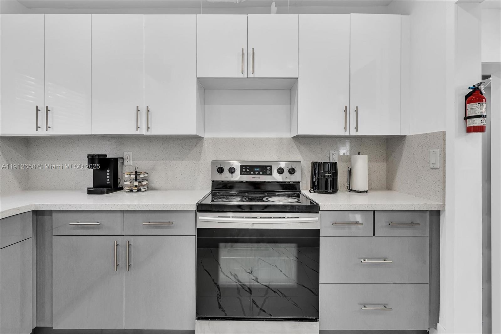 797 Northwest 35th Street Miami, FL 33127 - Photo 18 of 45 a kitchen with white cabinets and a stove with a sink