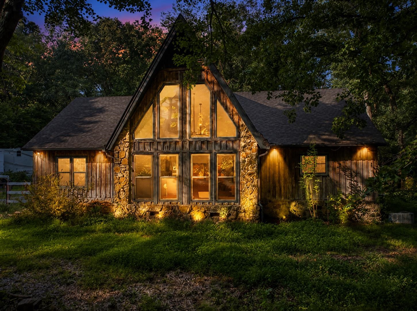 7320 McKinstry Road Moscow, TN 38057 - Photo 39 of 40 Dramatic A-frame architecture, floor-to-ceiling windows, and warm exterior lighting create an unforgettable first impression, blending rustic charm with a peaceful wooded setting for the perfect private retreat. This image has been virtually staged.