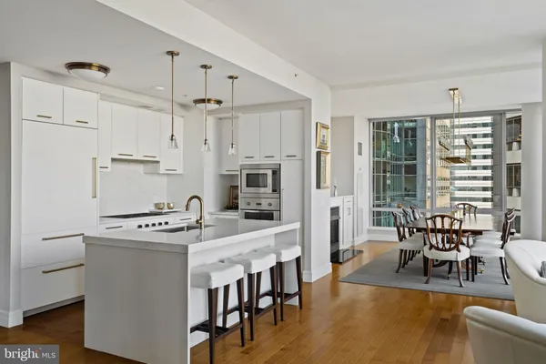 a large white kitchen with stainless steel appliances granite countertop a stove oven a sink dishwasher and white cabinets with wooden floor
