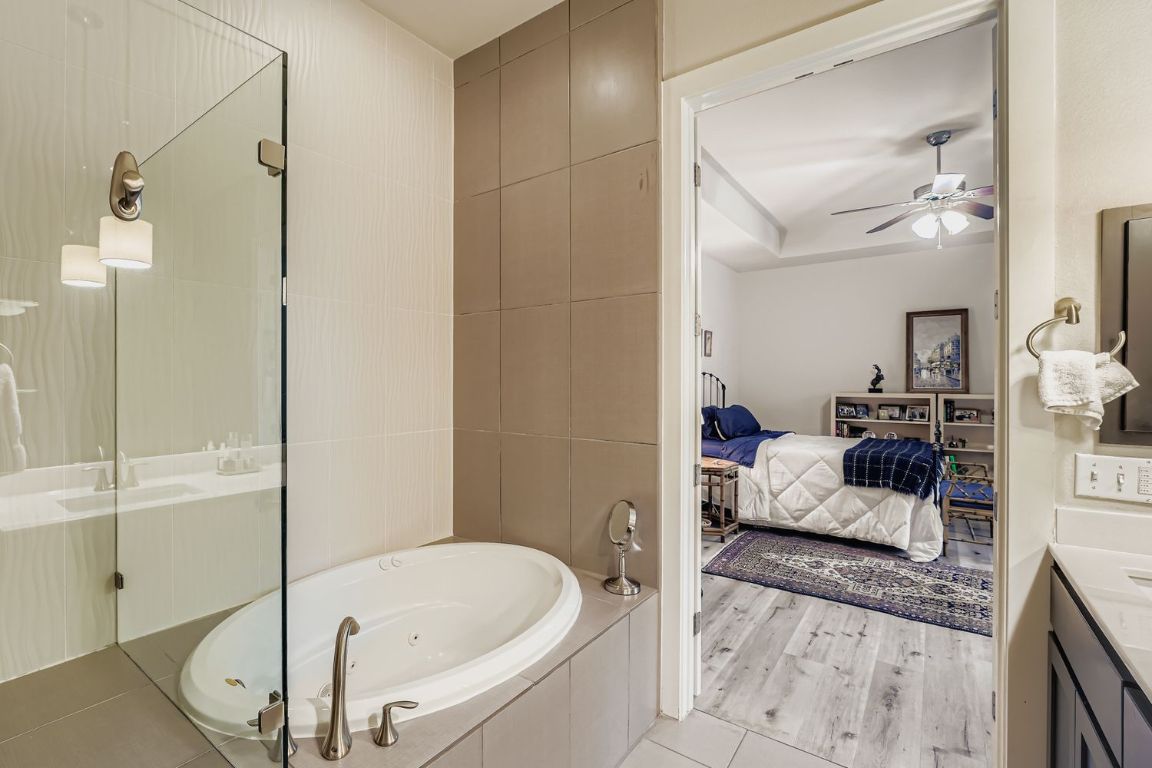 3905 Teaff Street Austin, TX 78723 - Photo 12 of 18 Main bath featuring vanity, a garden tub, connected bathroom, tile walls, and a walk in shower