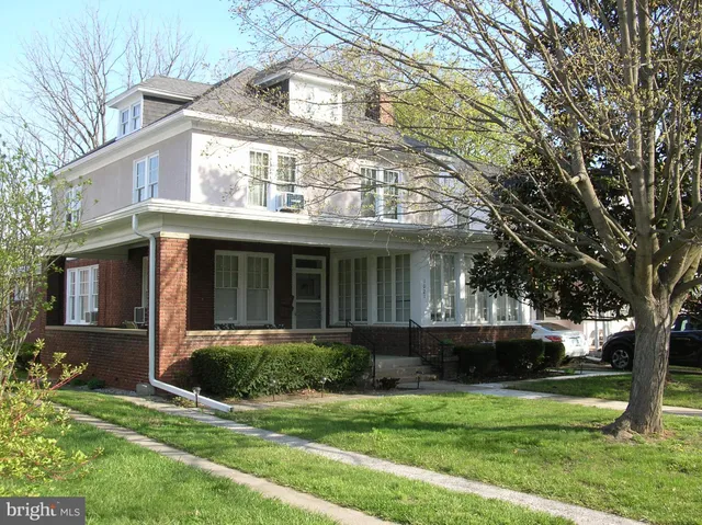 a view of a white house with a big yard and potted plants and large trees