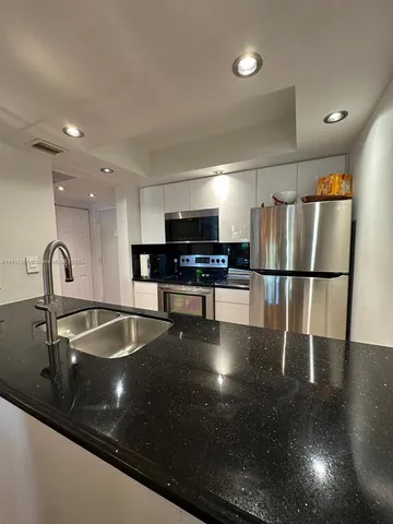 a kitchen with granite countertop a refrigerator and a sink