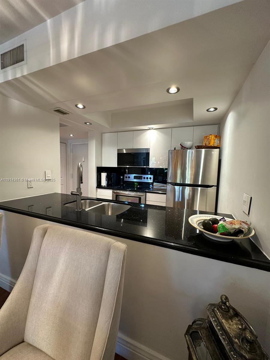 8180 Geneva Court, Unit 219 Doral, FL 33166 - Photo 4 of 19 a kitchen with stainless steel appliances granite countertop a sink refrigerator stove and microwave