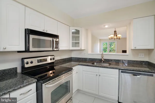 a kitchen with granite countertop a sink stove and microwave