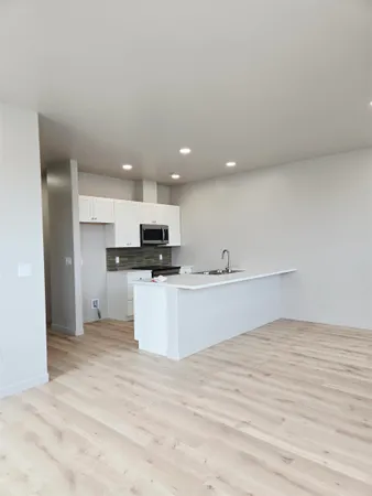 a view of an empty room with wooden floor and window