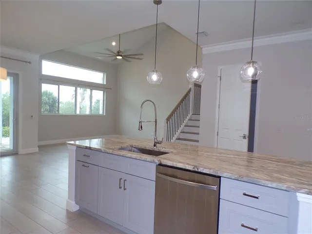 a view of a kitchen and a room with a chandelier fan