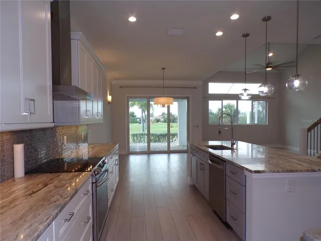 a view of a refrigerator in kitchen and an empty room with wooden floor